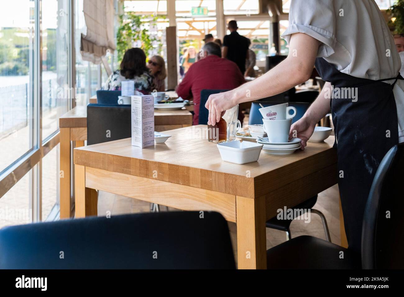 Un ouvrier de cuisine qui débarque des tables dans un restaurant animé de Newquay, en Cornouailles, au Royaume-Uni. Banque D'Images
