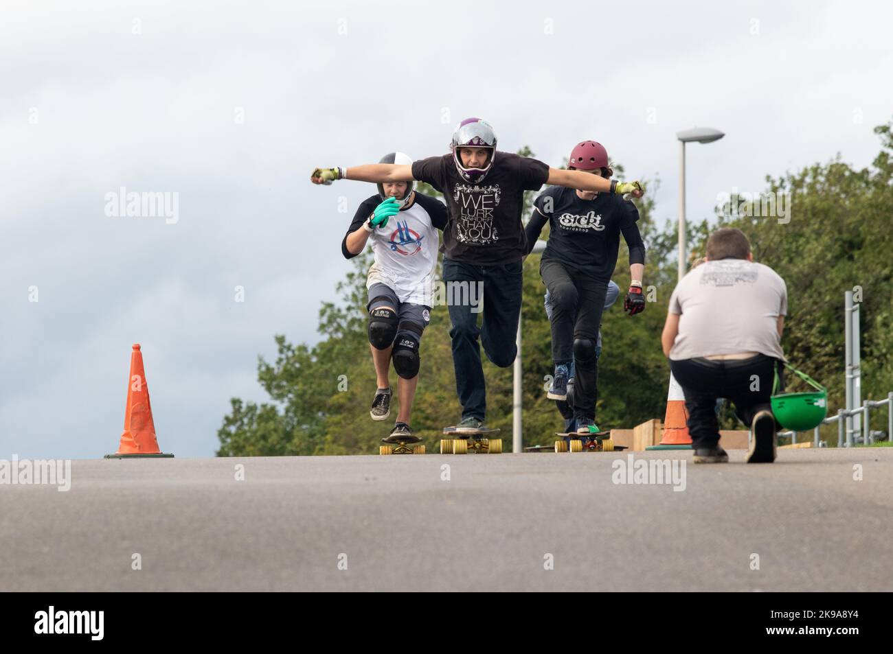 Les skateboarders pagayent pour commencer une descente tout en étant photographiés Banque D'Images