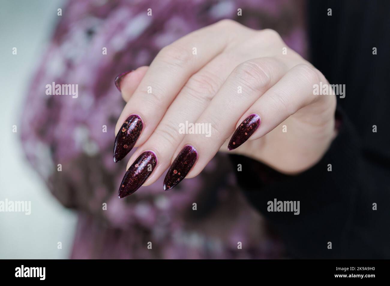 Femme main avec de longs ongles et une bouteille de vernis à ongles bordeaux  violet foncé Photo Stock - Alamy