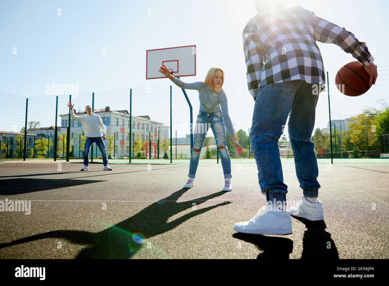 Trois adolescents jouant au streetball avec un ballon de basket-ball dans la cour de l'école après les cours. Concept de sport, activités de loisirs, passe-temps, équipe, amitié Banque D'Images