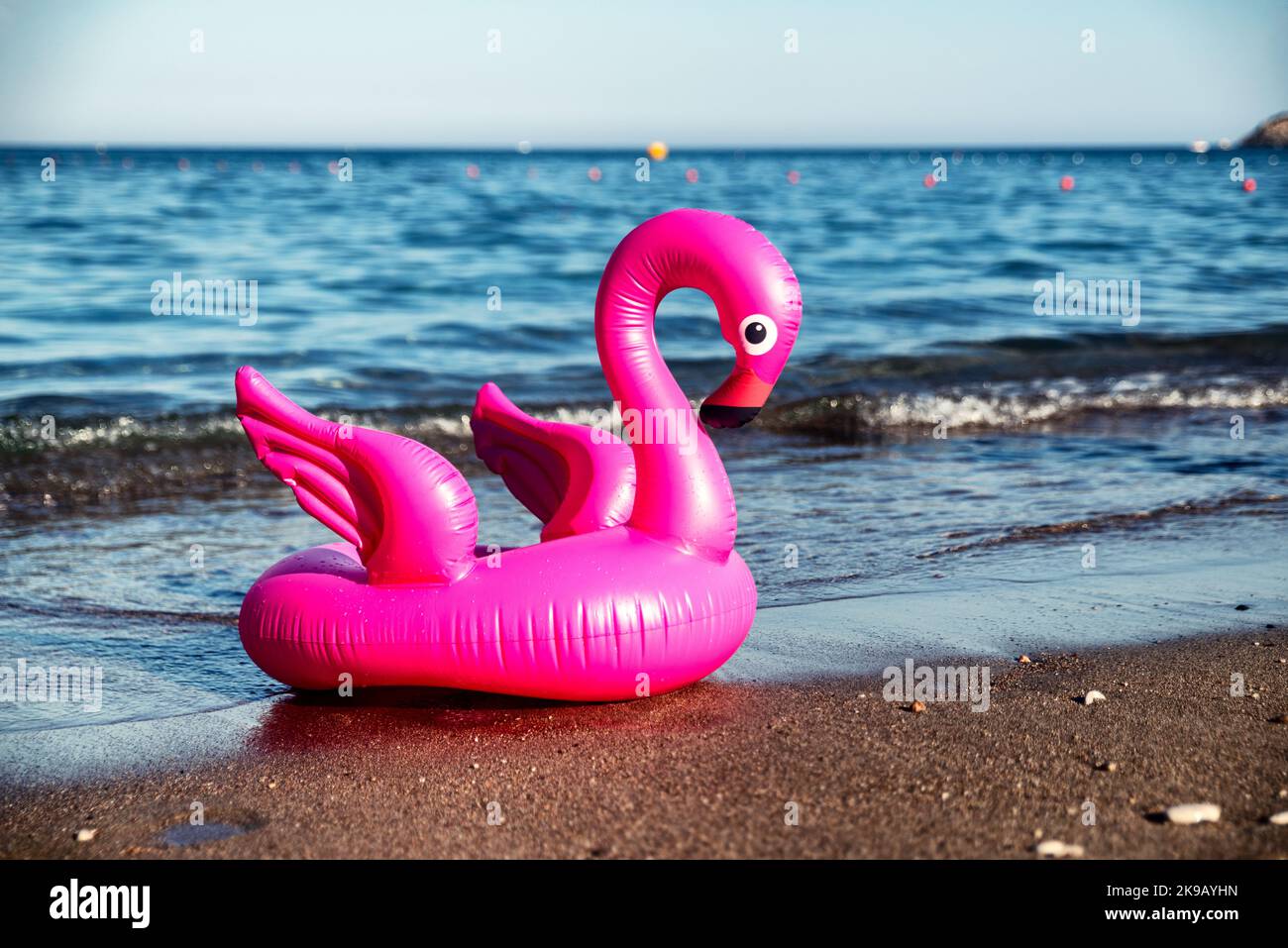 Flamant rose gonflable sur une plage de sable avec la mer en arrière-plan. Banque D'Images