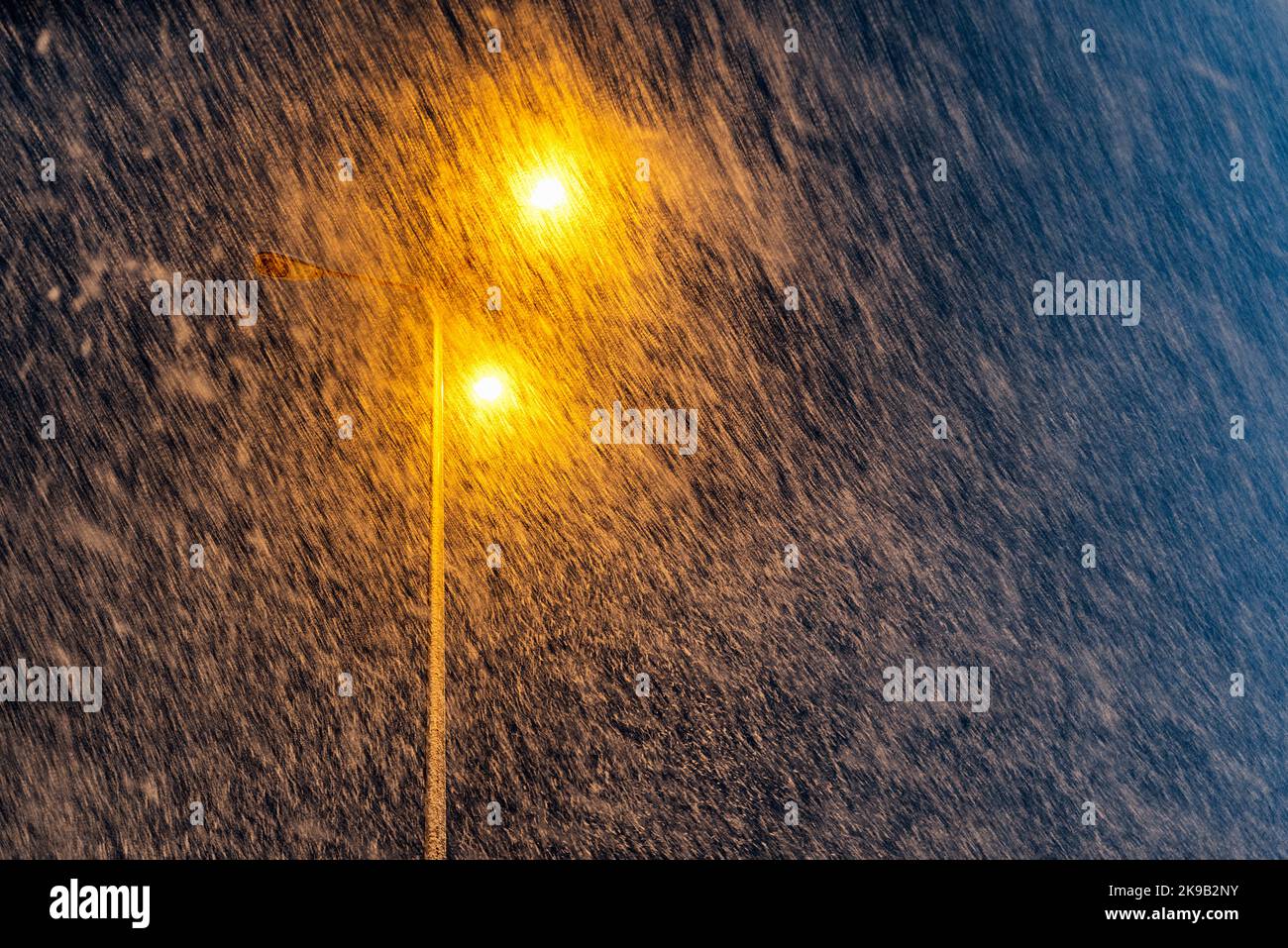 Tempête de neige. Nuit enneigée en ville. Feu de rue en arrière-plan. Banque D'Images