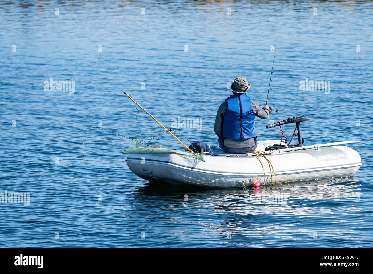 Un homme seul utilise un bateau de caoutchouc Gala et une tige pour pêcher dans le lac Simcoe. Banque D'Images