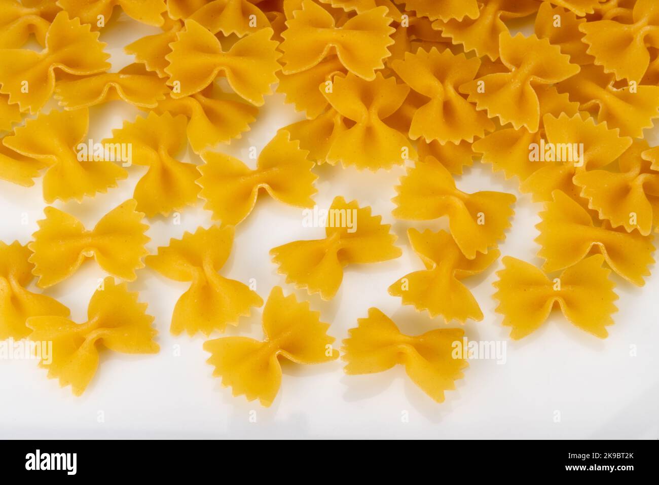 Pâtes italiennes appelées farfalle, macaroni cru en forme de noeud papillon isolé sur blanc, vue de dessus Banque D'Images