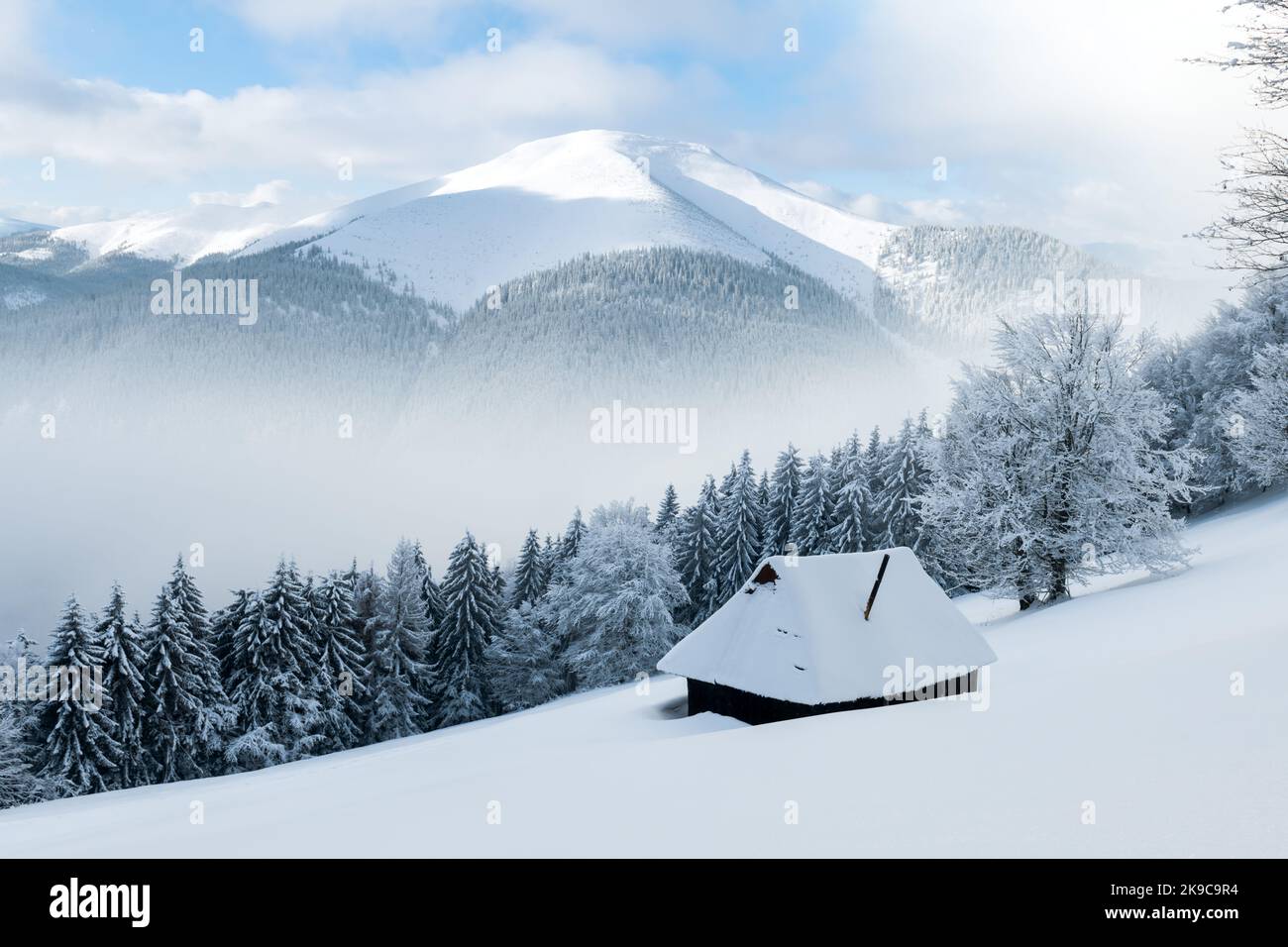 Paysage fantastique avec des montagnes enneigées, des arbres et une cabine en bois. Carpathian montagnes, Ukraine, Europe Banque D'Images