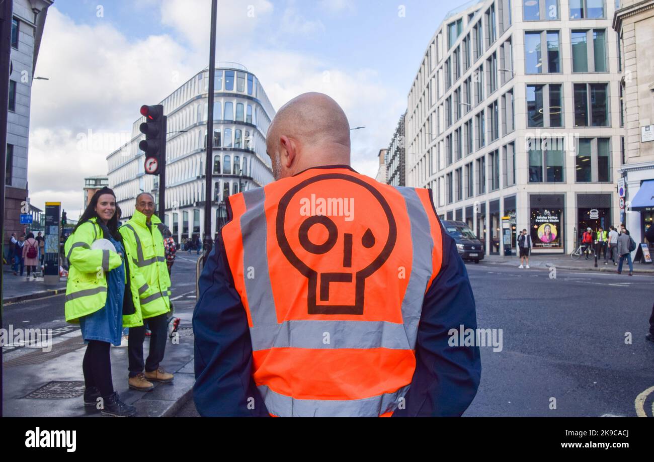 Londres, Royaume-Uni. 27th octobre 2022. Un manifestant porte une veste orange avec le logo Just Stop Oil pendant la démonstration. Les militants du programme Just Stop Oil ont collé leurs mains et se sont enfermés dans des tuyaux métalliques qui bloquent les rues autour de la gare de Mansion House dans la City de Londres, le quartier financier de la capitale, alors qu'ils poursuivent leurs protestations exigeant que le gouvernement cesse d'émettre de nouvelles licences de combustibles fossiles. Crédit : SOPA Images Limited/Alamy Live News Banque D'Images