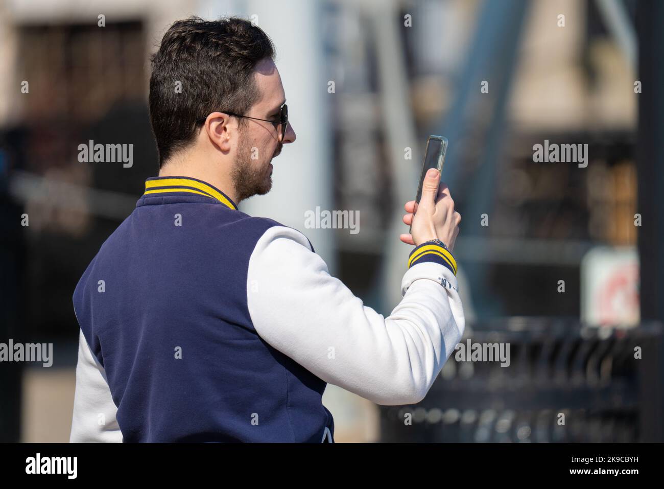 Jeune homme blanc marchant et parlant sur un téléphone cellulaire dans les rues de Toronto, au Canada. Jeune adulte ayant une conversation par téléphone. Banque D'Images