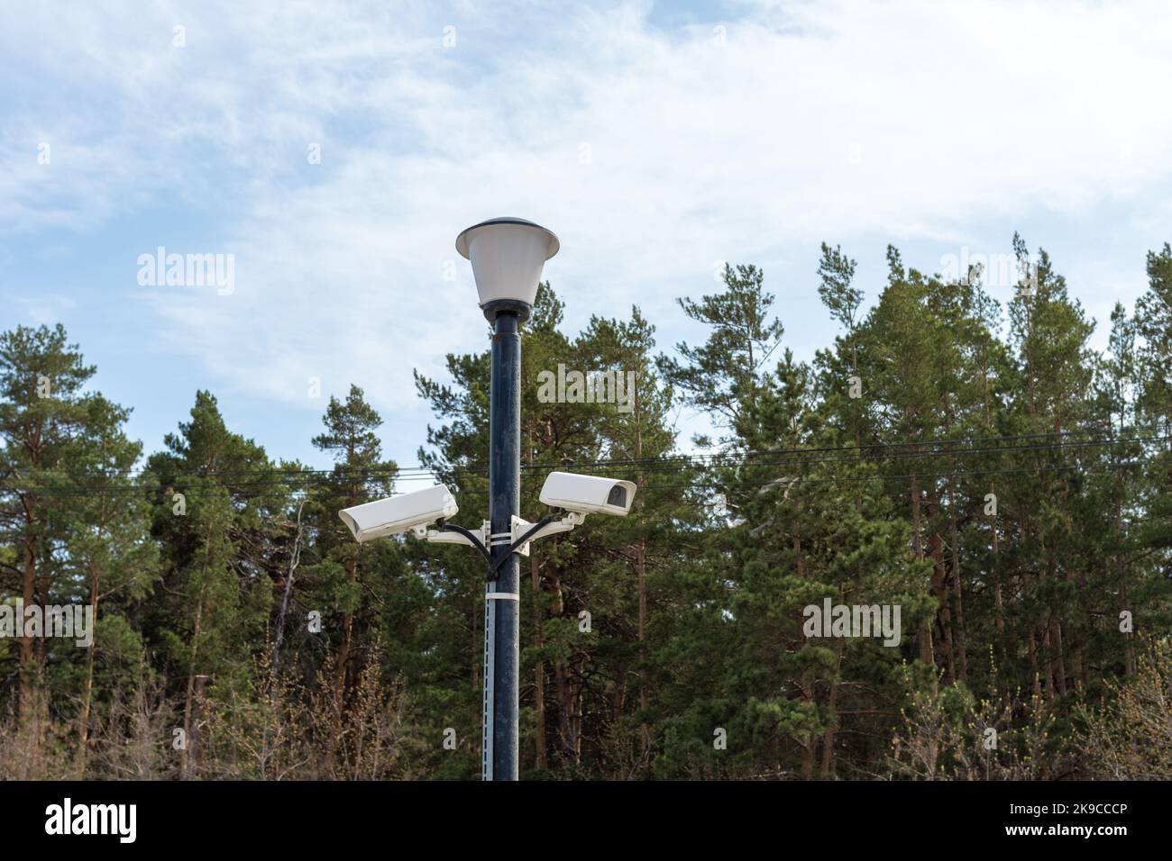 Caméras de surveillance montées sur un lampadaire sur le côté d'une route forestière. Caméra de vidéosurveillance de sécurité. Sécurité dans la ville. Le tournage caché de ce qui est happeni Banque D'Images