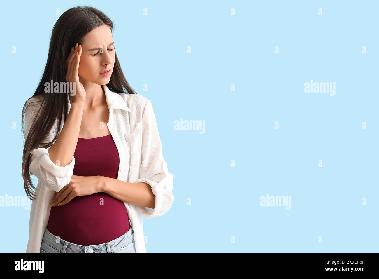 Jeune femme enceinte avec saignement de nez sur fond bleu Photo Stock -  Alamy