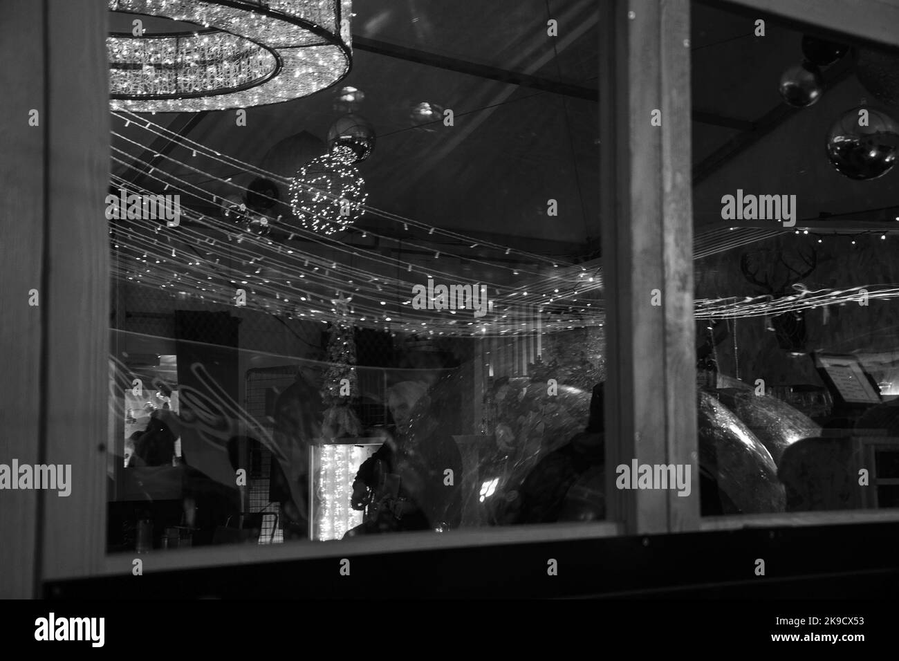 PARIS, FRANCE - 6 JANVIER 2019 : ambiance de Noël. Vue à travers la fenêtre dans le café au marché de Noël. Illuminations festives, musiciens jouant g Banque D'Images