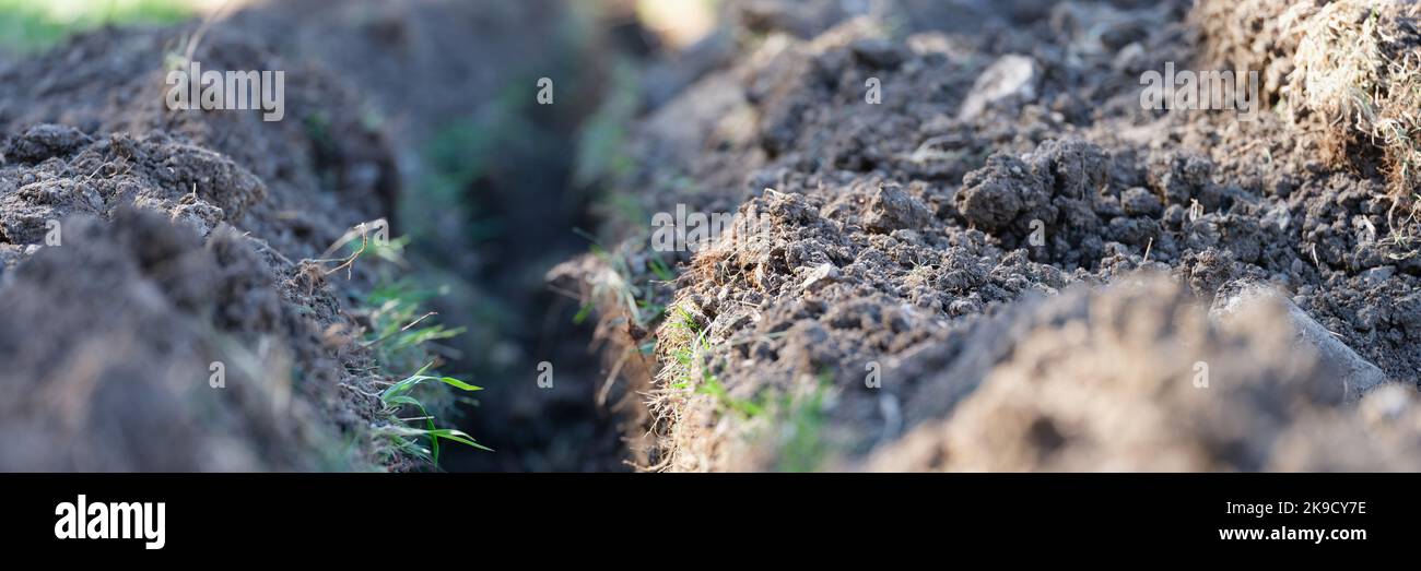 Creusez la tranchée. Travaux de terrassement et creusement de tranchées. Une longue tranchée de terre est creusée pour la pose de tuyaux ou de fibres optiques Banque D'Images