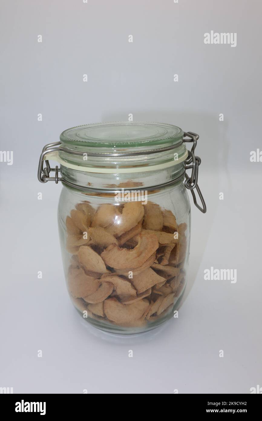 Pot en verre rempli de tranches de pomme déshydratées et séchées sur fond blanc Banque D'Images