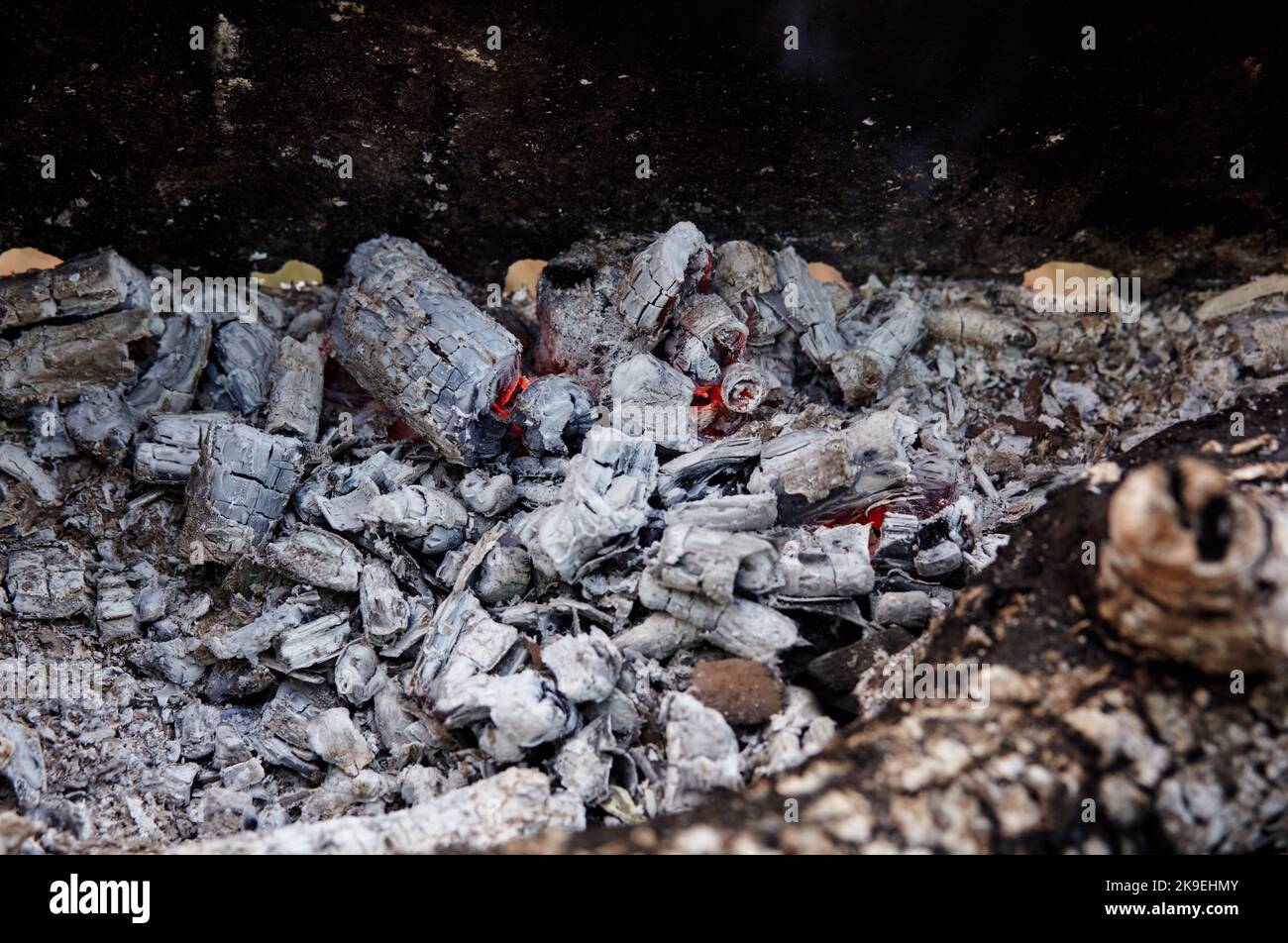 Charbon de bois couvant dans un barbecue. Morceaux épars d'émbres dans le foyer mélangés à de la cendre. Cendres après pour préparer les aliments à l'extérieur Banque D'Images