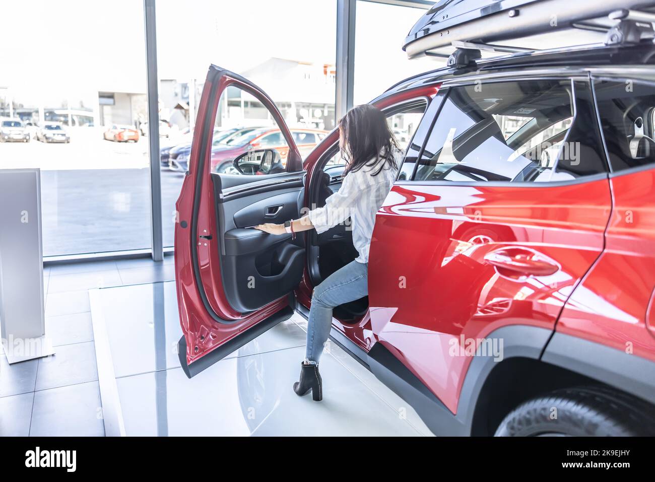 Un jeune client profite de l'inspection d'une nouvelle voiture dans le magasin. Banque D'Images