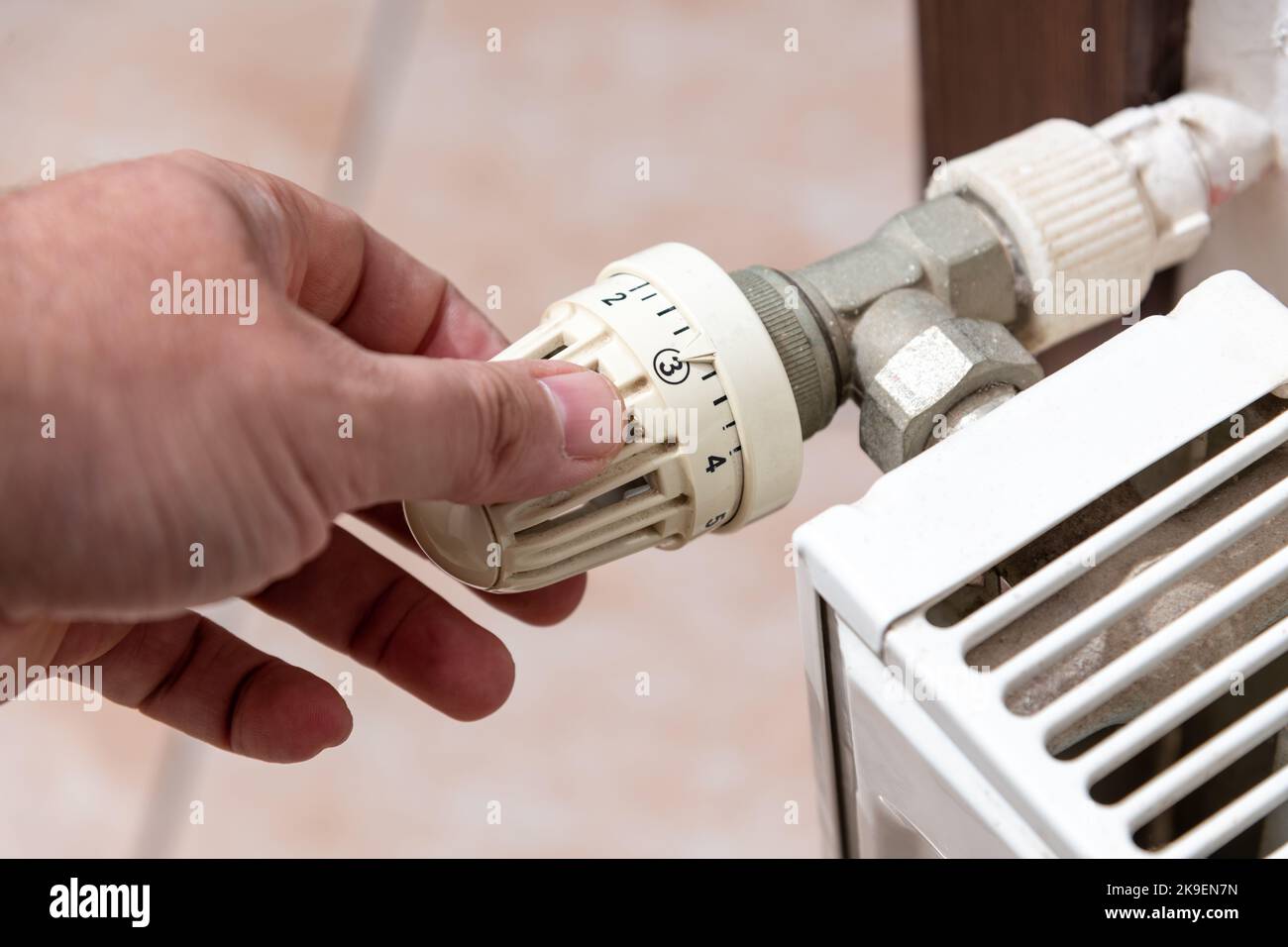 La main qui ferme la vanne de radiateur de la chaudière en Europe, où il y a une pénurie de gaz naturel en raison de la guerre russe Banque D'Images