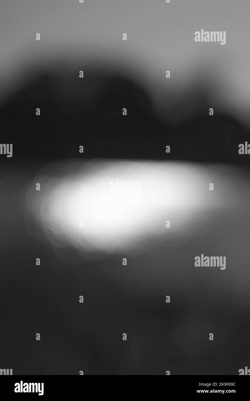 Vue floue et rêveuse de la lumière du soleil scintillant sur la surface de la pondina noir et blanc monochrome. Banque D'Images
