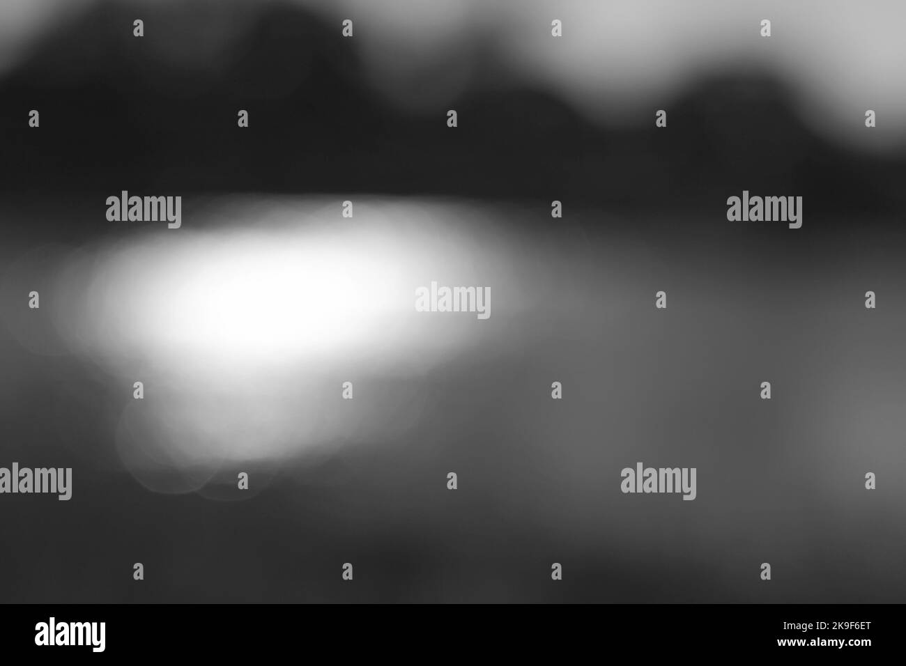Vue floue et rêveuse de la lumière du soleil scintillant sur la surface de la pondina noir et blanc monochrome. Banque D'Images