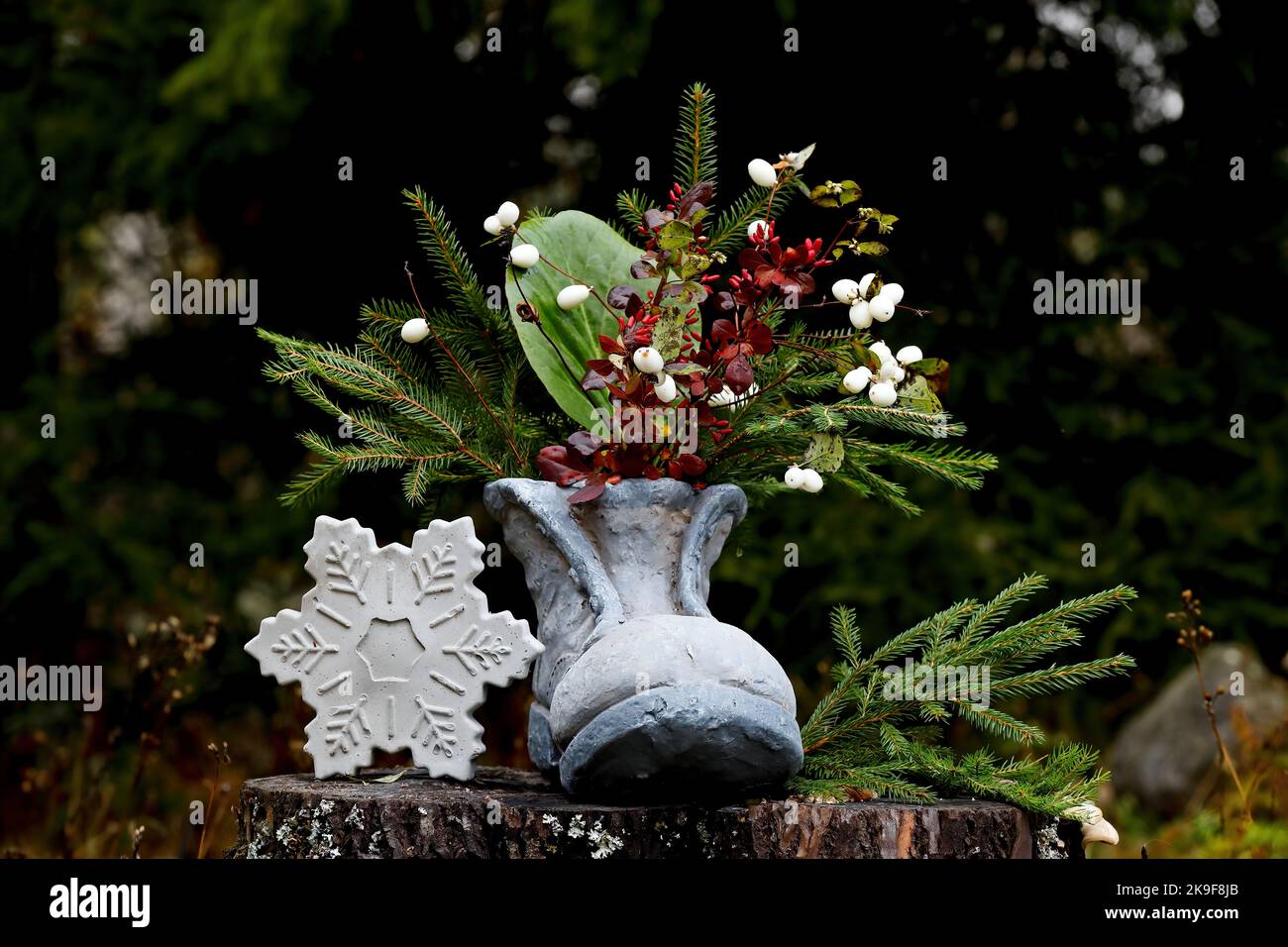 Une chaussure grise avec branches en sapin et flocons de neige en béton Banque D'Images