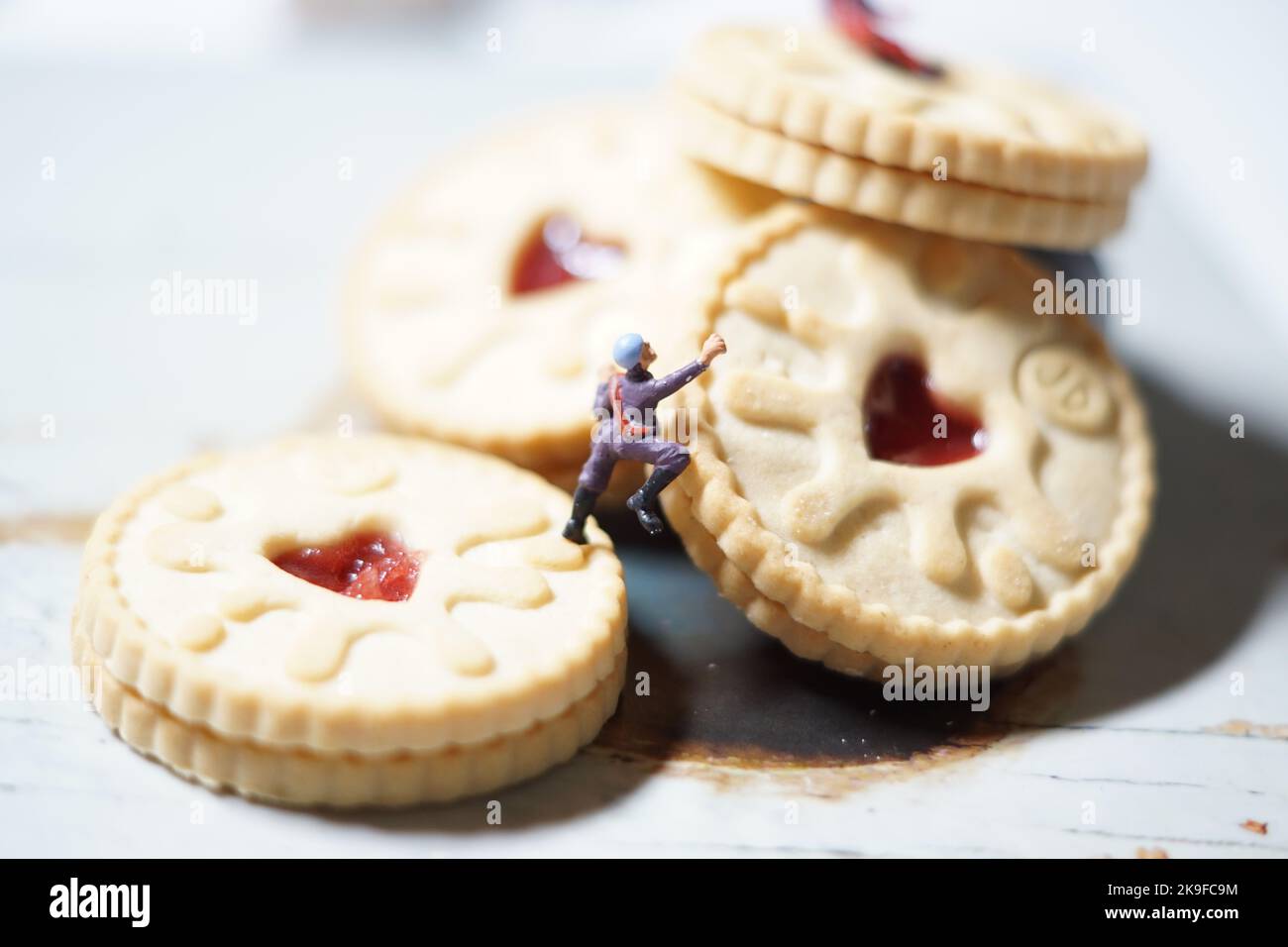 Miniature d'hommes et de biscuit montagne, une série de photographies utilisant des personnes miniatures, des biscuits à la confiture et des cailloux montrant un monde miniature d'images. Banque D'Images