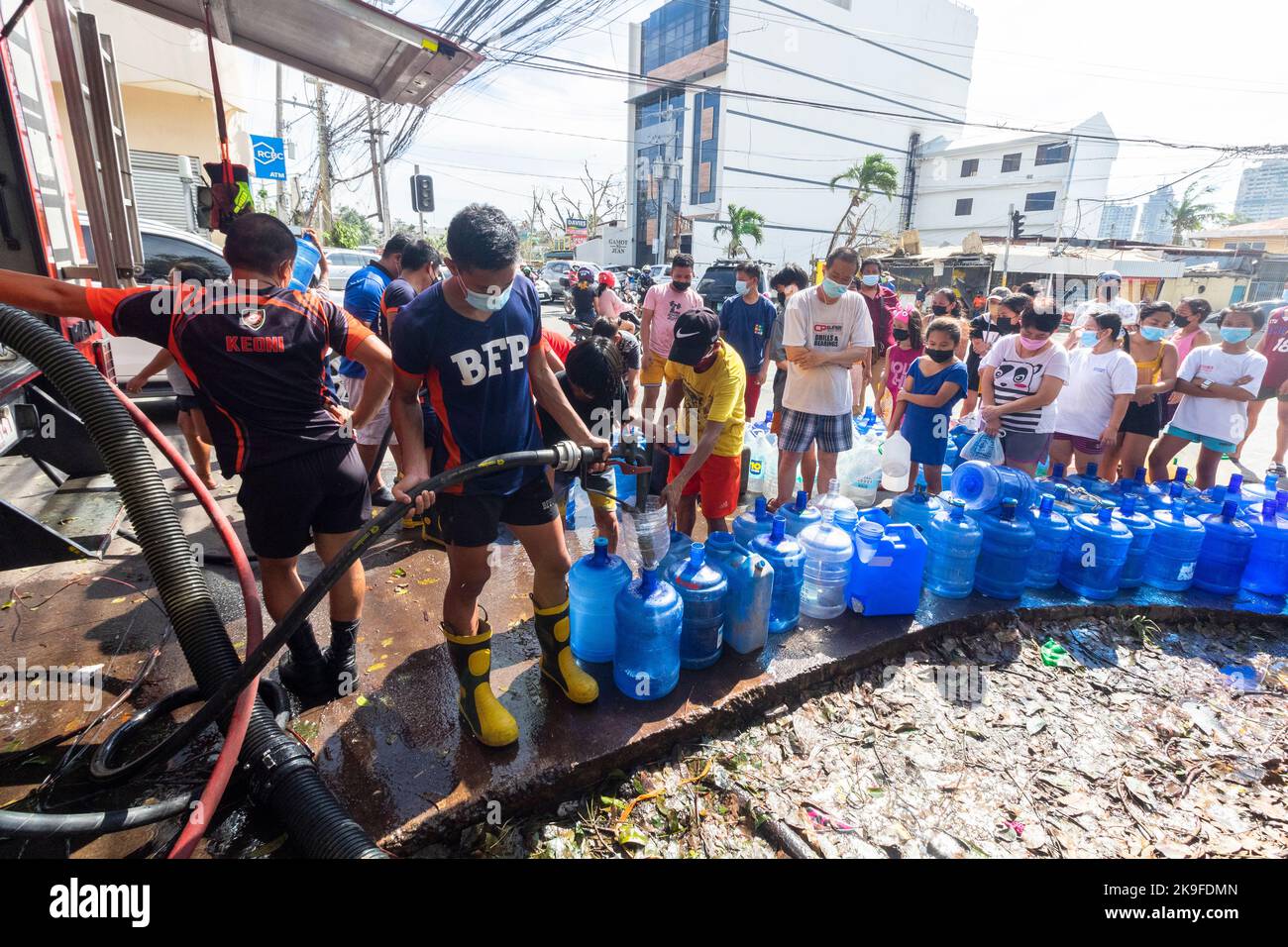 Des membres du Bureau de la protection contre les incendies fournissent de l'eau potable aux résidents après une pénurie d'eau provoquée par le typhon Rai à Cebu, aux Philippines Banque D'Images