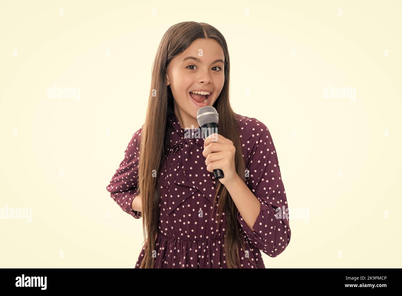 Adolescente avec microphone chantant sur fond blanc avec visage drôle. Chantant belle chanteuse fille tenir microphone. Portrait de sourire heureux Banque D'Images