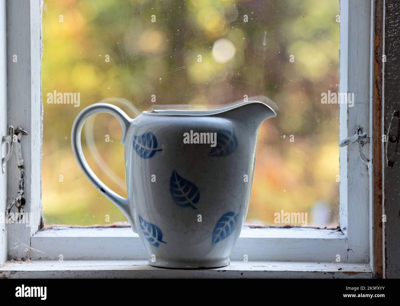 Un vieux pot à lait sale sur un rebord de fenêtre Banque D'Images