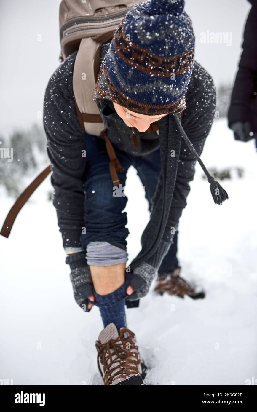 Je suis aussi chaud que possible. Un jeune homme tirant ses chaussettes tout en dehors sur la neige. Banque D'Images