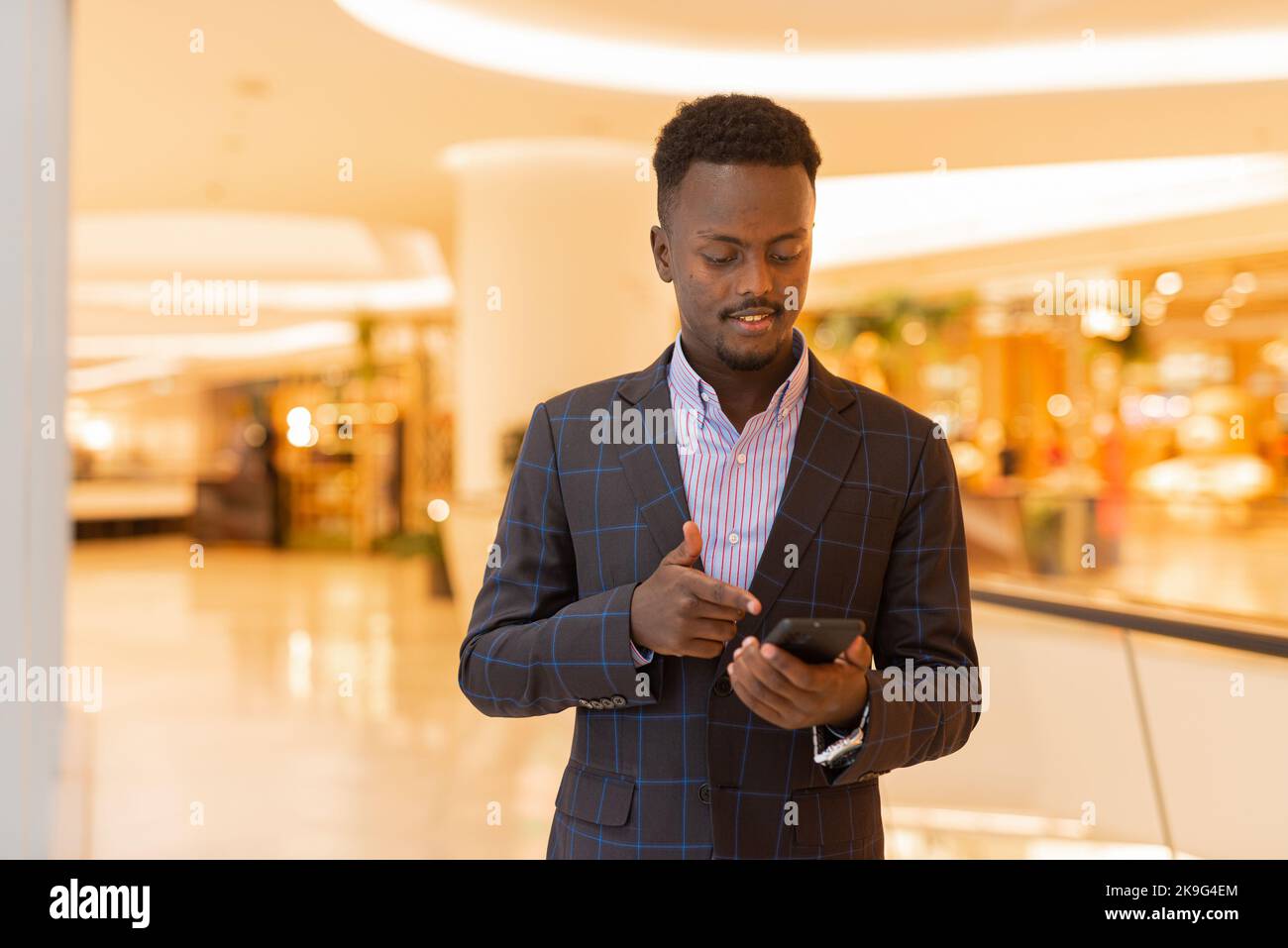 Portrait d'un homme d'affaires africain élégant utilisant un téléphone portable Banque D'Images