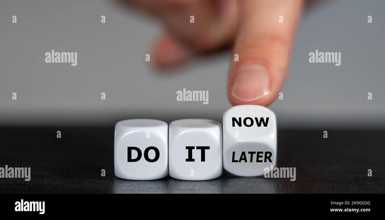 La main fait tourner les dés et change l'expression « do it later » en « do it now ». Banque D'Images