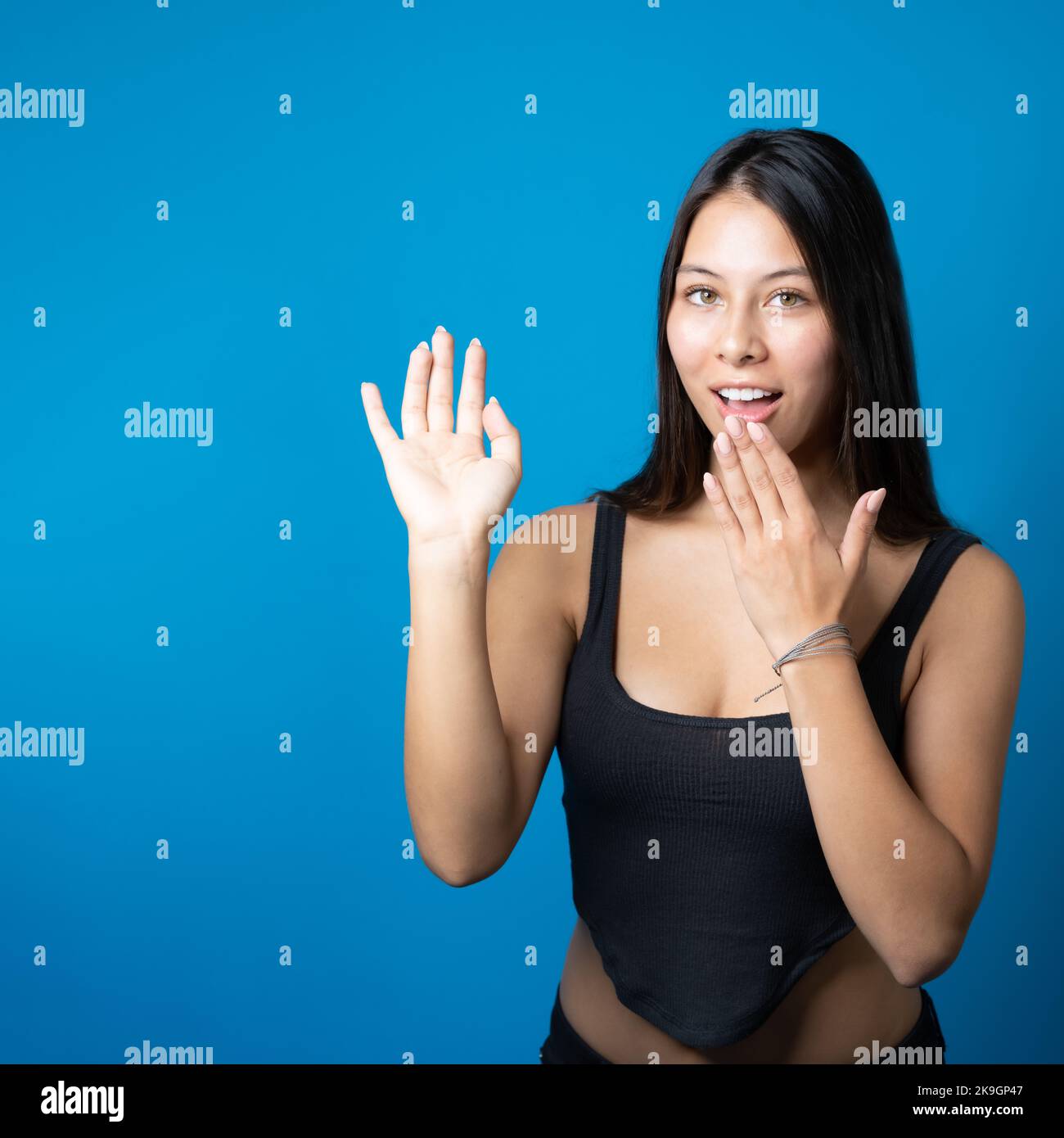 Jeune femme à la mode avec une tenue secrète et présentant un espace de copie sur sa paume isolée sur fond bleu Banque D'Images