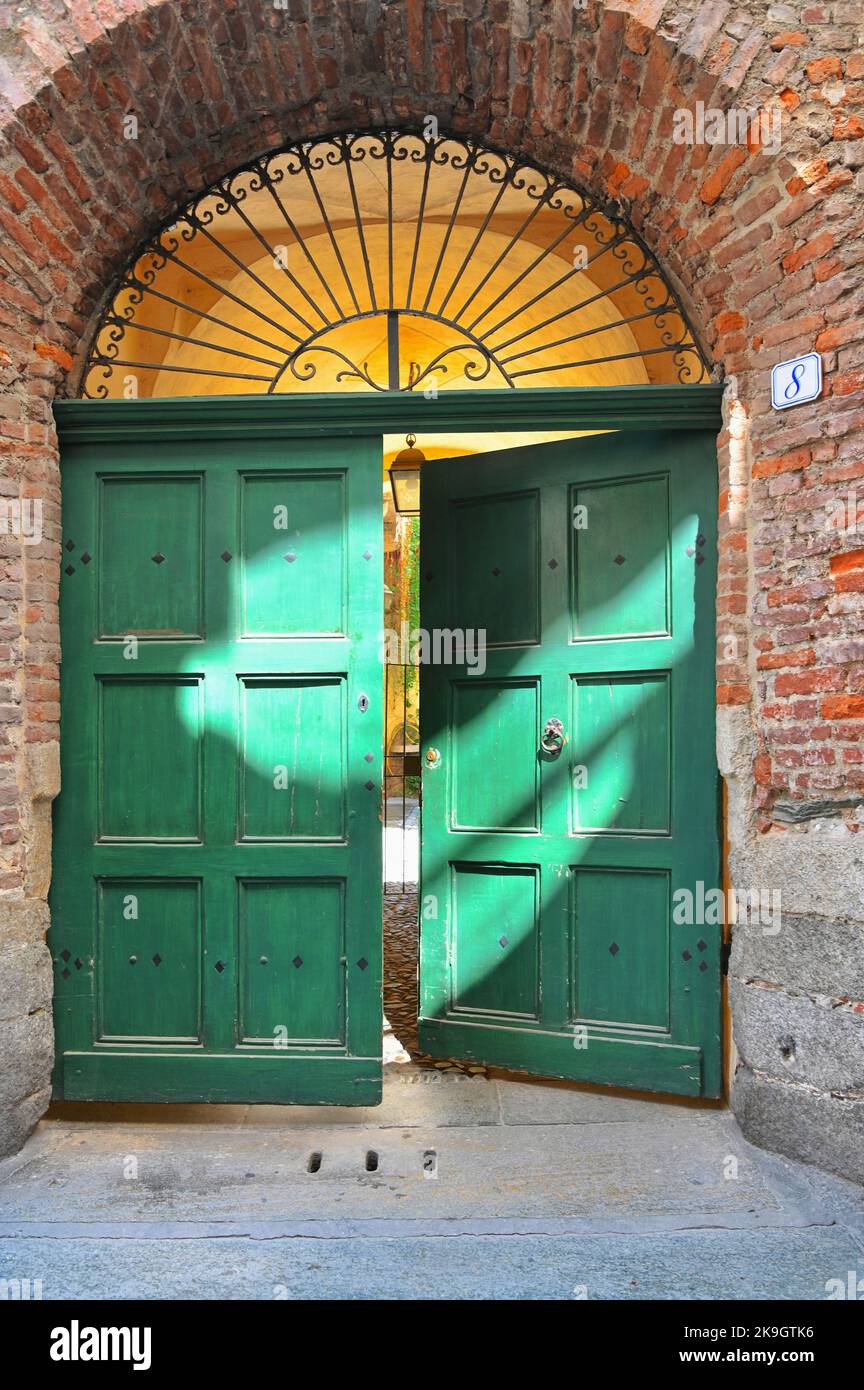 Un portail ancien fait de porte en bois vert et de fer forgé sur le mur rustique de briques rouges Banque D'Images