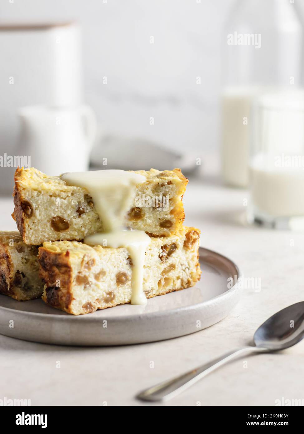 Portion de cocotte de fromage cottage ou de pudding aux raisins secs versée avec du lait condensé sur fond de table blanc Banque D'Images