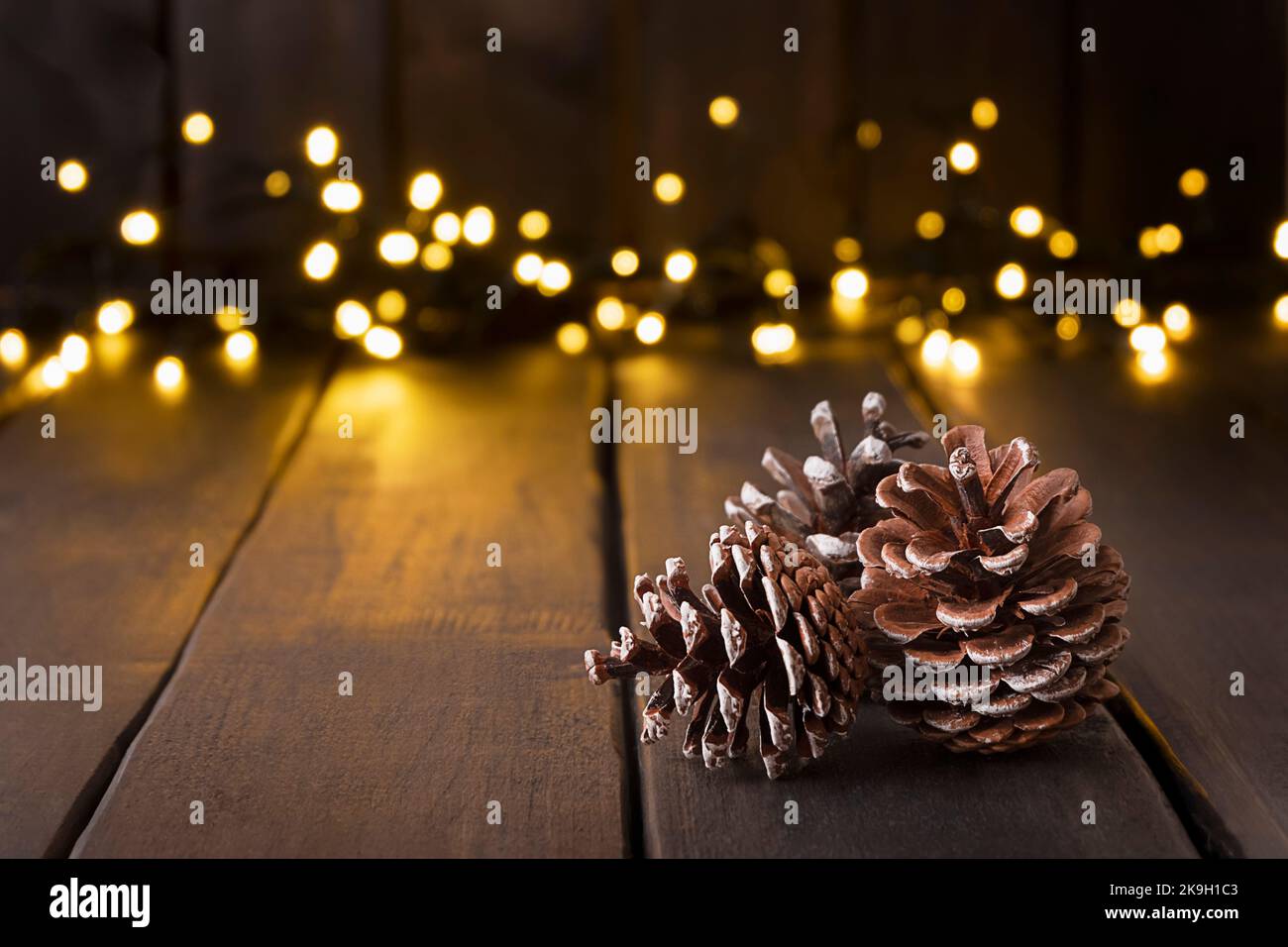 Fond festif avec des cônes sur une table en bois avec bokeh clair, espace de copie Banque D'Images