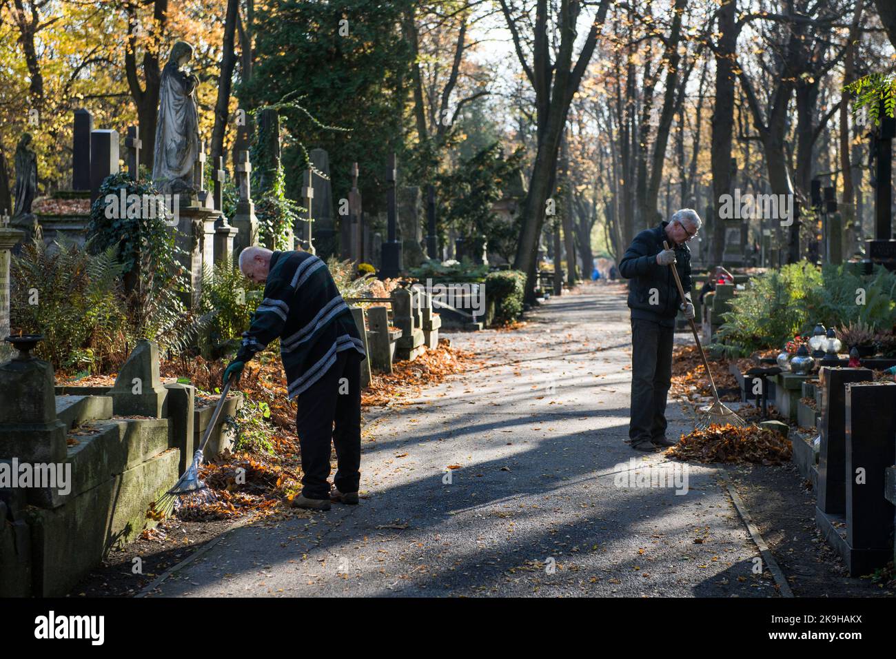 Deux hommes balayent les feuilles du cimetière historique de Powazki