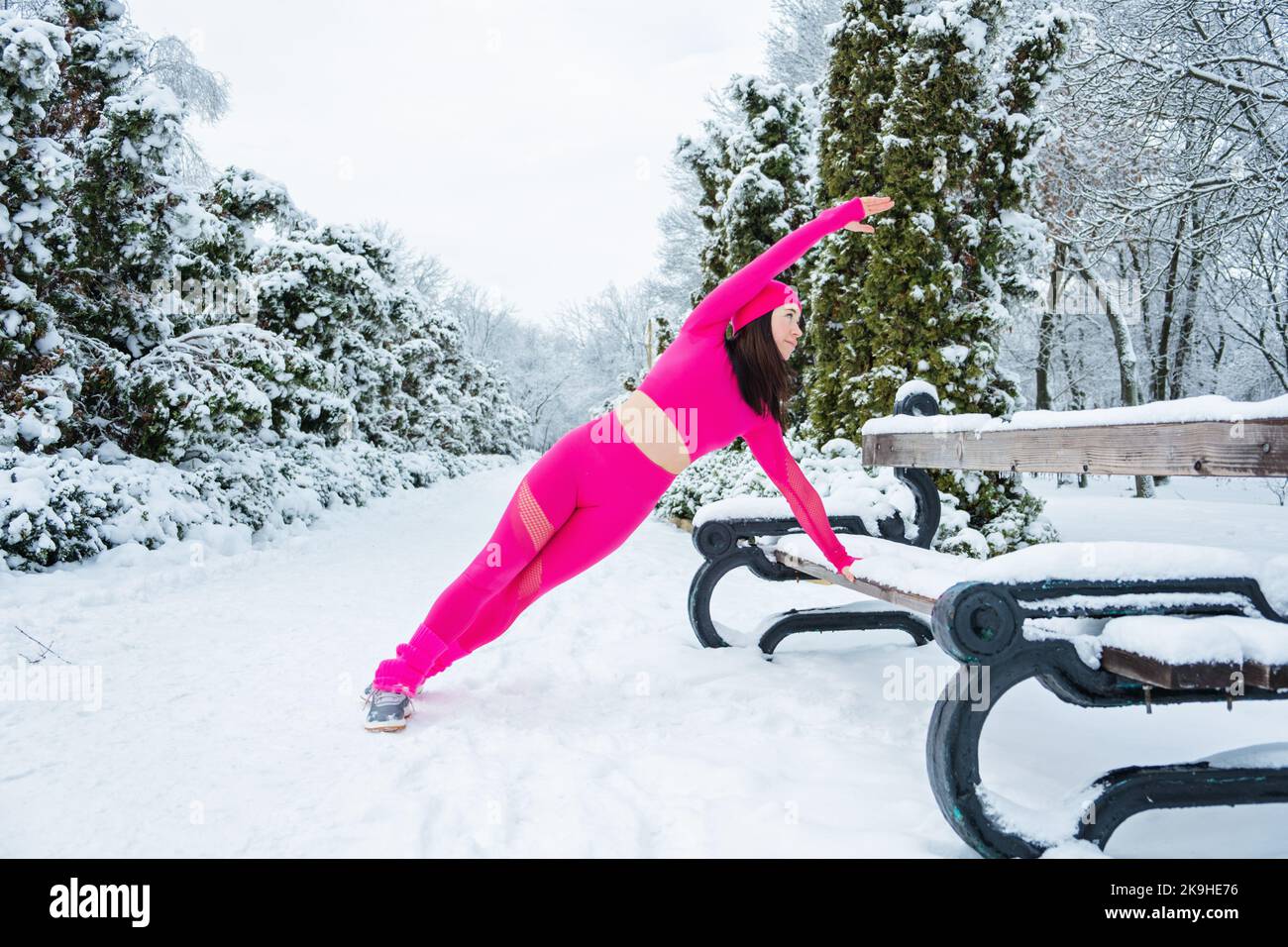 Entraînement d'hiver, exercice en plein air. En hiver, faites de l'exercice par temps froid. Sportswoman faisant des exercices d'étirement et se préparant à courir dans la nature à Banque D'Images