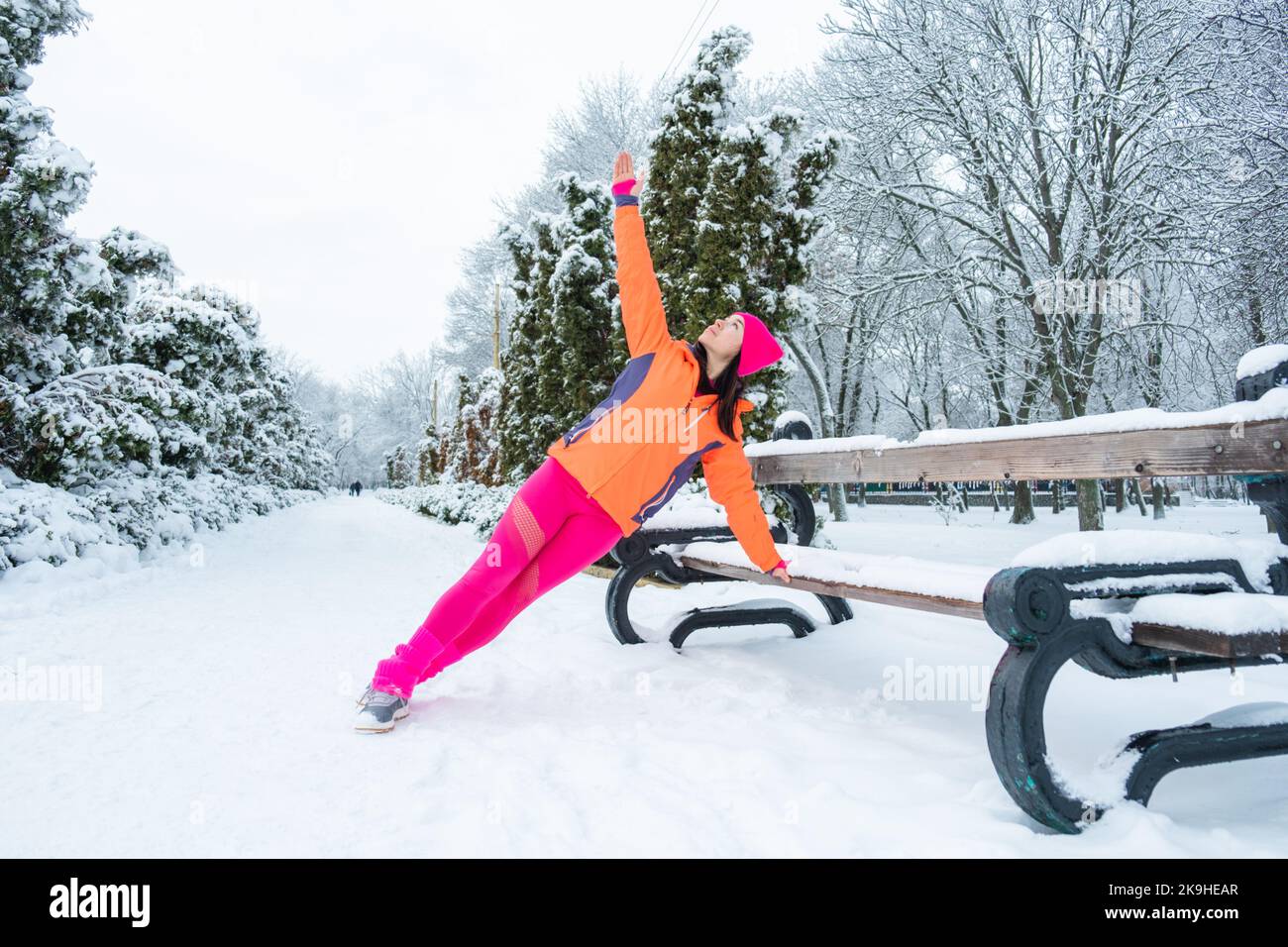 Entraînement d'hiver, exercice en plein air. En hiver, faites de l'exercice par temps froid. Sportswoman faisant des exercices d'étirement et se préparant à courir dans la nature à Banque D'Images