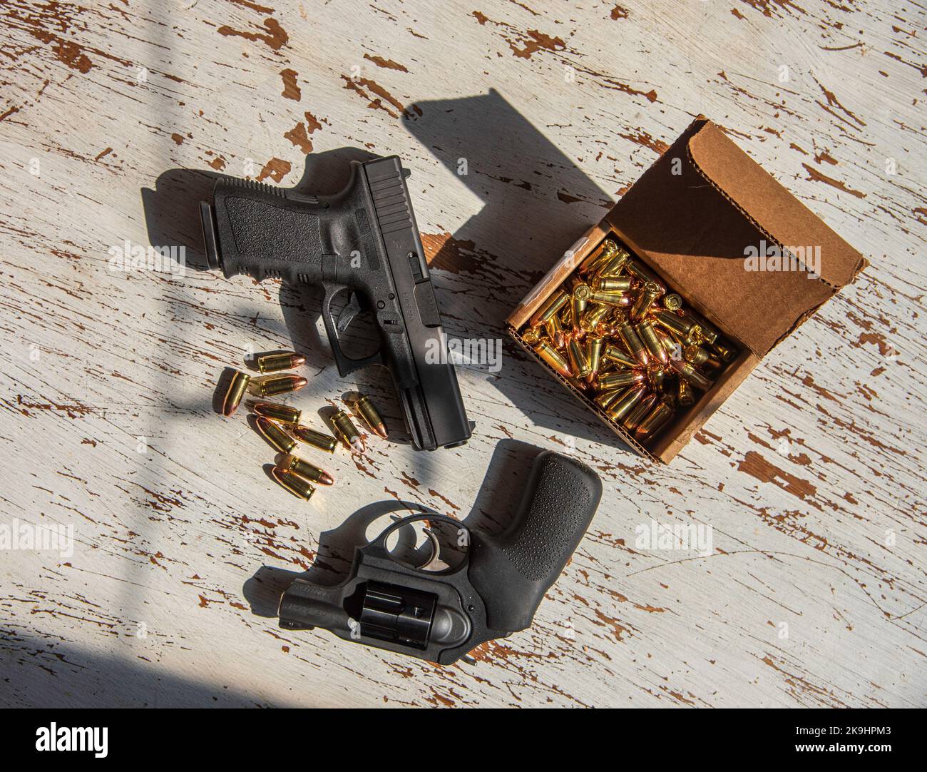 Un noir, Glock 19, 9mm, pistolet et un Ruger, 9mm, snub nez, revolver sur une table en bois avec quelques balles. Banque D'Images