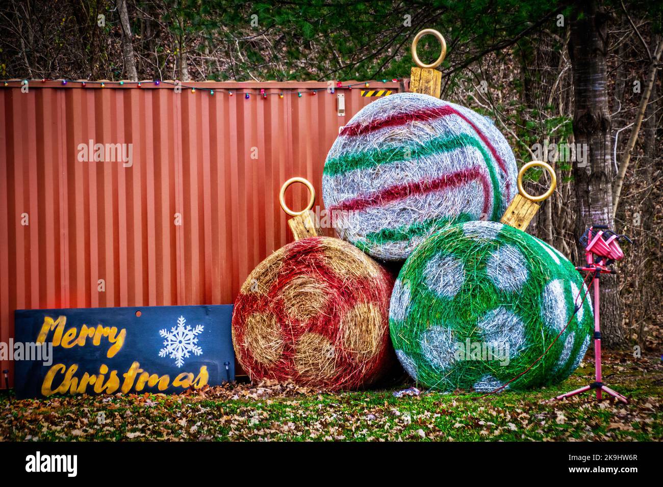 Campagne - scène rurale - grandes balles rondes de foin peintes comme des ornements de Noël avec signe de Joyeux Noël devant le wagon et les bois réaffectés - Banque D'Images
