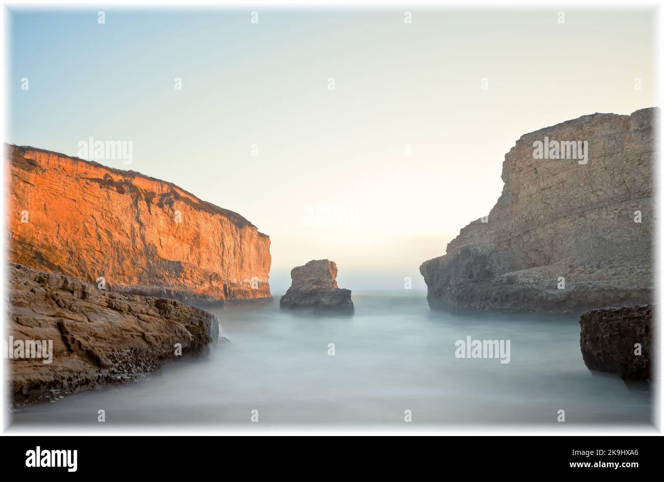 Une scène côtière à couper le souffle avec une falaise rocheuse imposante et Shark fin Rock s'élevant de l'océan à Shark fin Cove, Davenport, Californie, au coucher du soleil. Banque D'Images