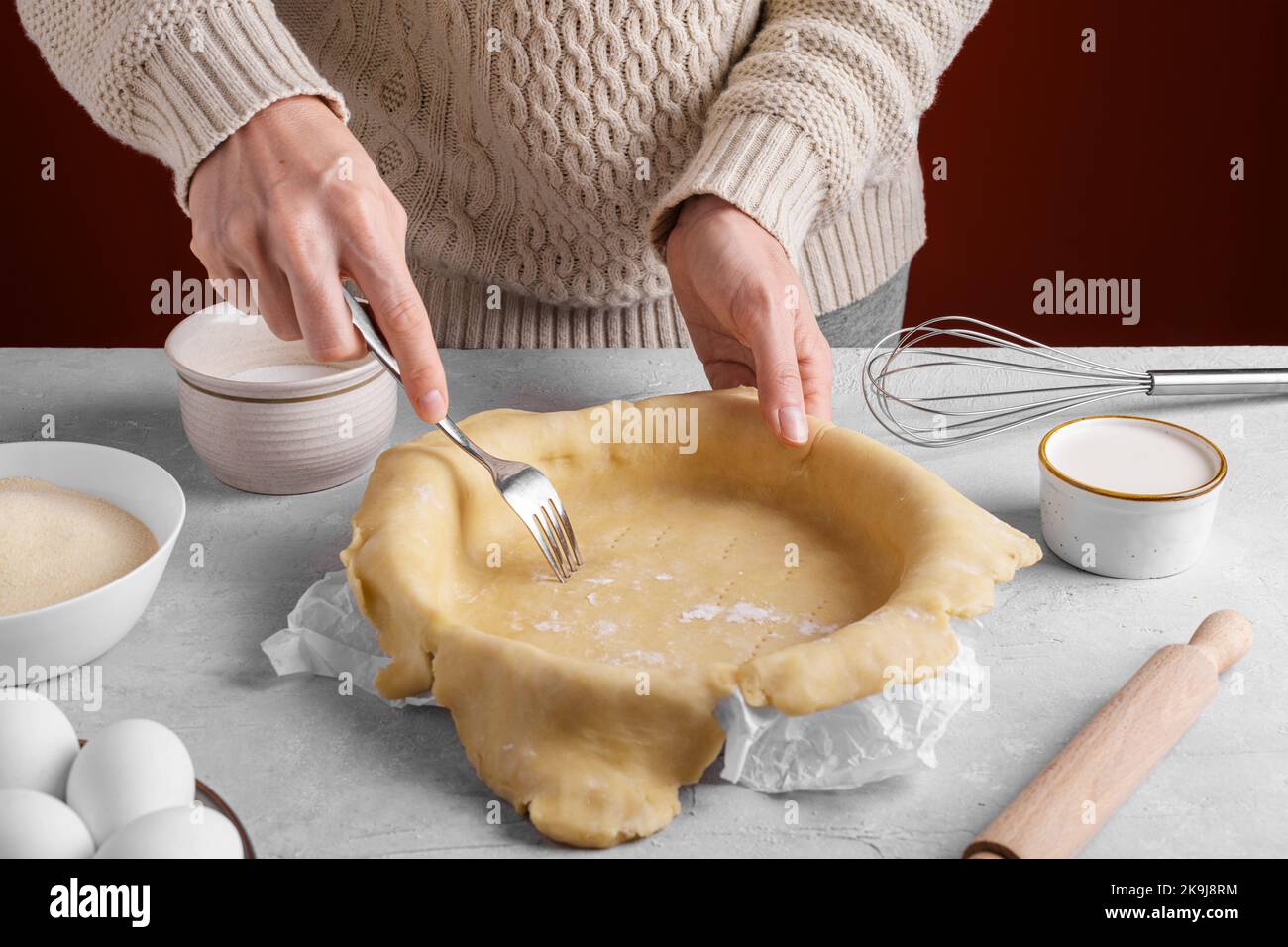 Femme utilisant la fourchette pour percer les trous sur toute la pâte sur la table dans la cuisine avant de cuire la croûte de tarte maison. Des mains de femmes authentiques qui font une ba Banque D'Images