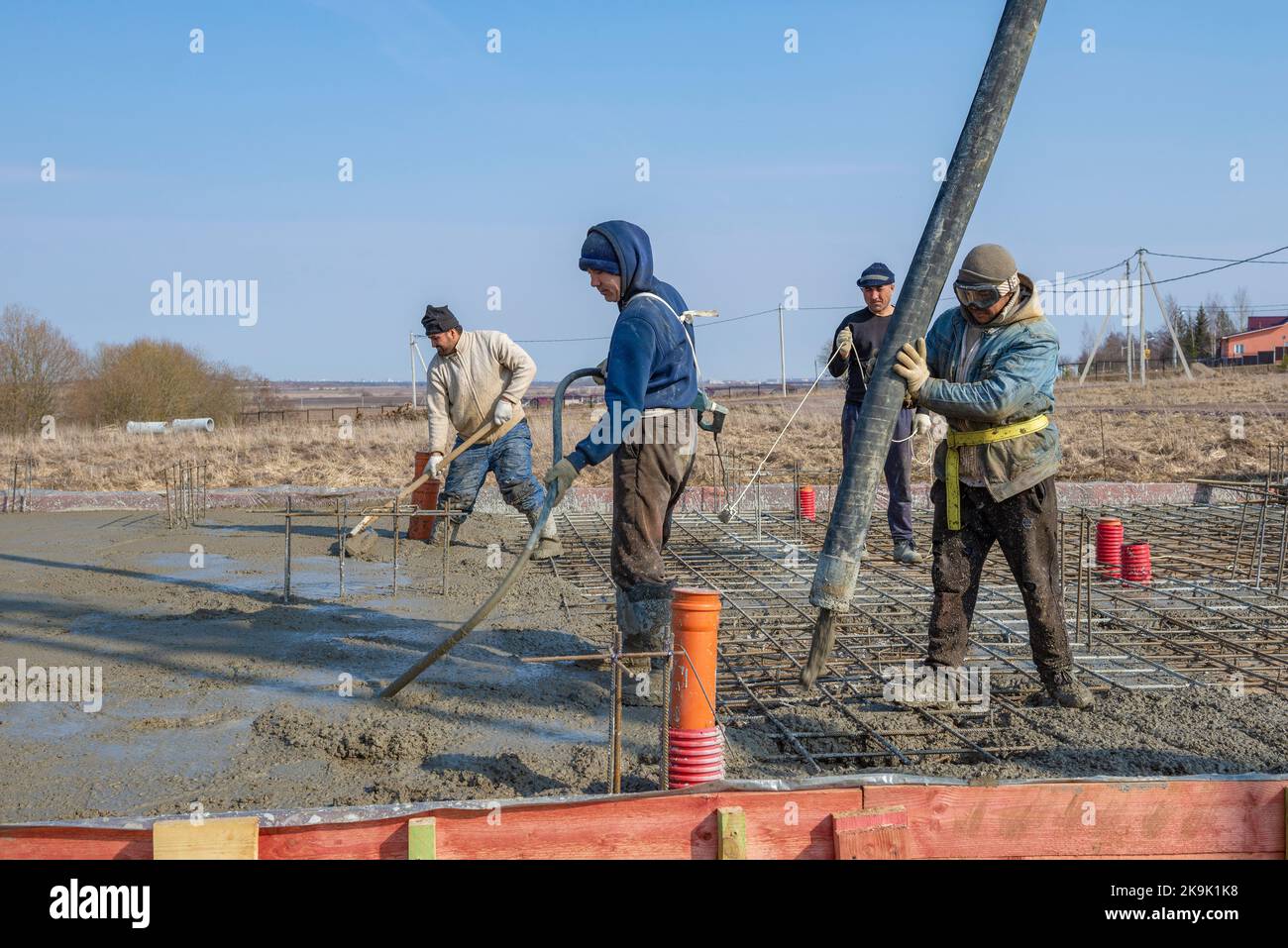 RÉGION DE LENINGRAD, RUSSIE - 28 MARS 2021 : les travailleurs invités servent la fondation d'une maison de campagne le jour du printemps Banque D'Images