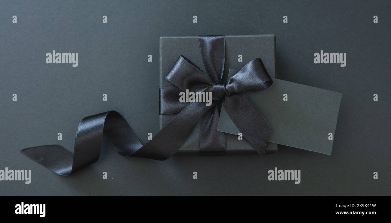 Soldes du Vendredi fou et cadeaux de Noël. Boîte cadeau avec ruban noir et carte vide isolée sur fond noir, Banque D'Images