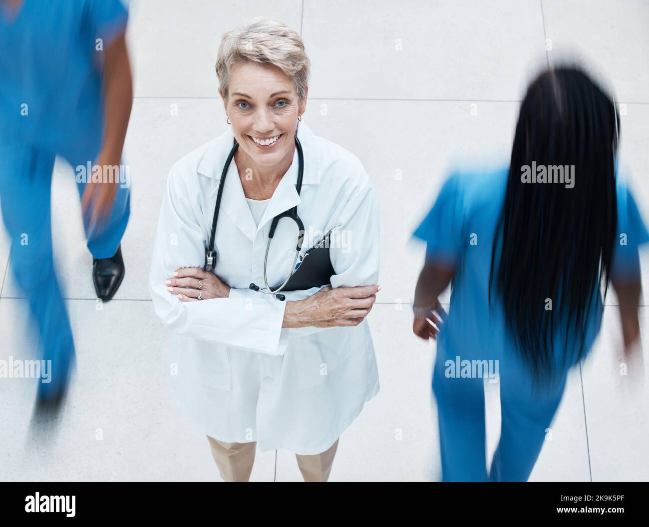 Portrait, heureux et médecin dans l'hôpital occupé debout avec les bras croisés après consultation. Bonheur, médecine et professionnel de la santé senior avec Banque D'Images