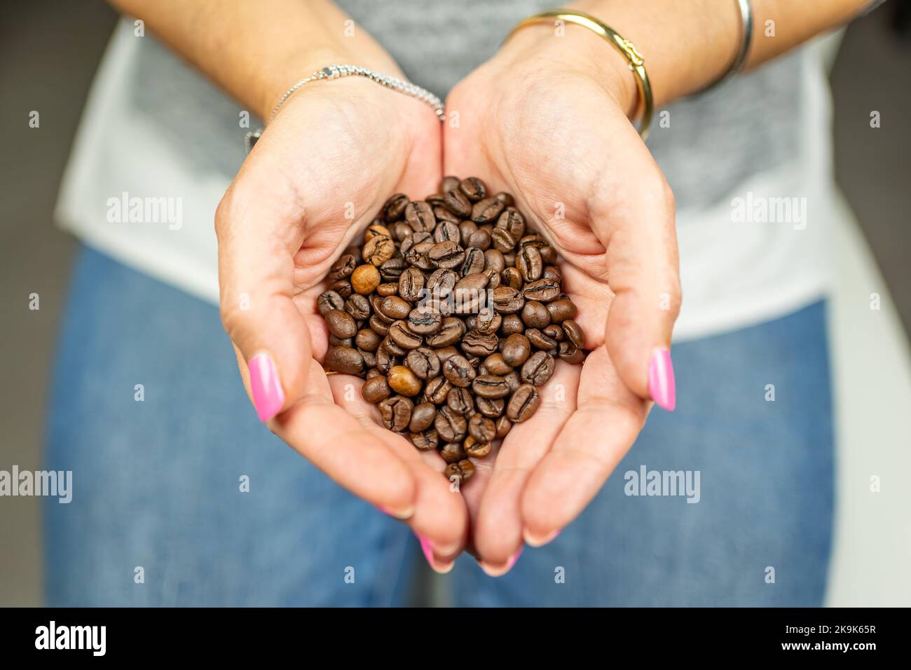 Femme tenant dans ses mains torréfié grains de café avec un grand arôme. Banque D'Images