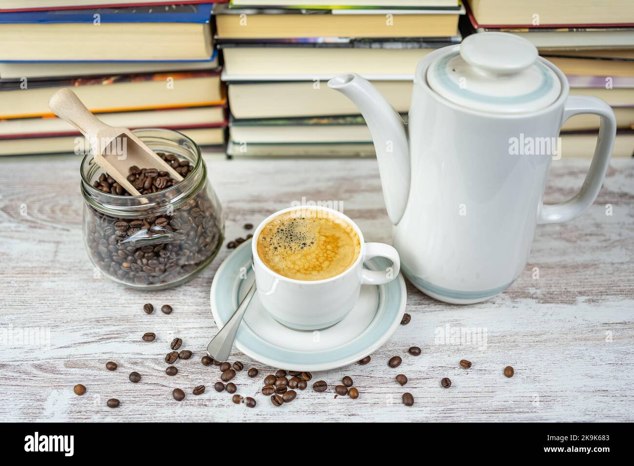 Tasse à café avec machine à café en porcelaine et pot en verre avec grains de café avec un fond de livres dans la bibliothèque Banque D'Images