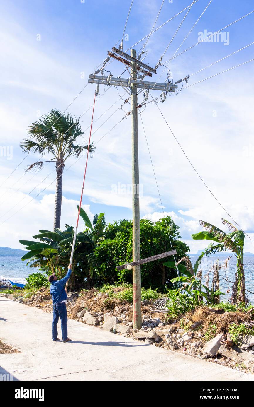 Un lineman philippin travaillant sur un poteau électrique à Batangas, Philippines Banque D'Images