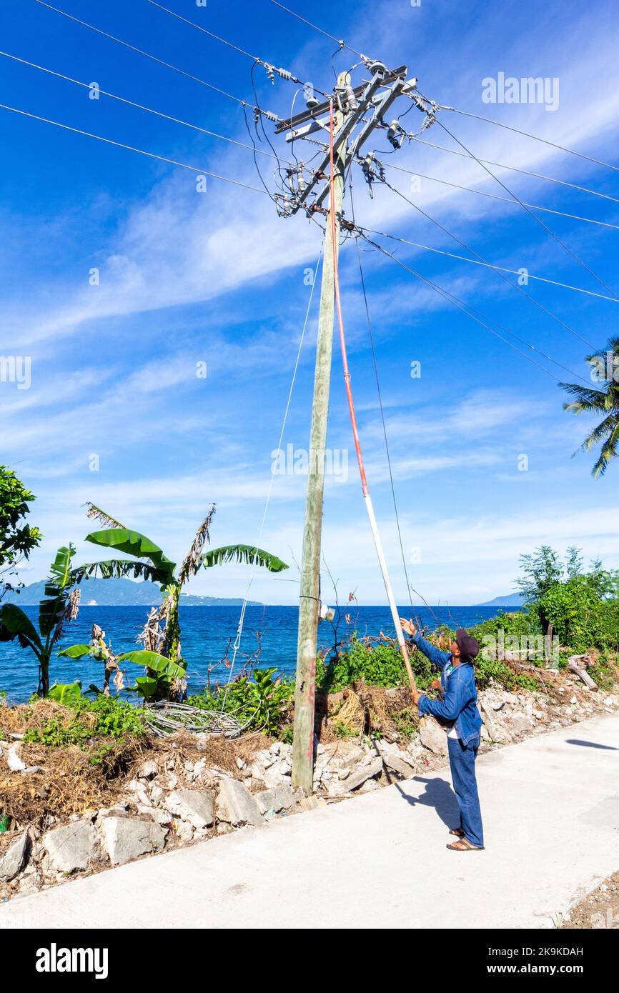 Un lineman philippin travaillant sur un poteau électrique à Batangas, Philippines Banque D'Images