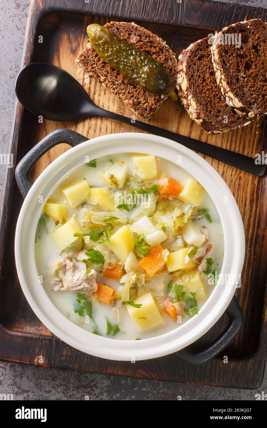 Soupe de pickle à l'aneth zupa ogorkowa est l'une des soupes traditionnelles les plus populaires en Pologne près de la casserole sur le plateau en bois vue verticale du dessus de l'ab Banque D'Images