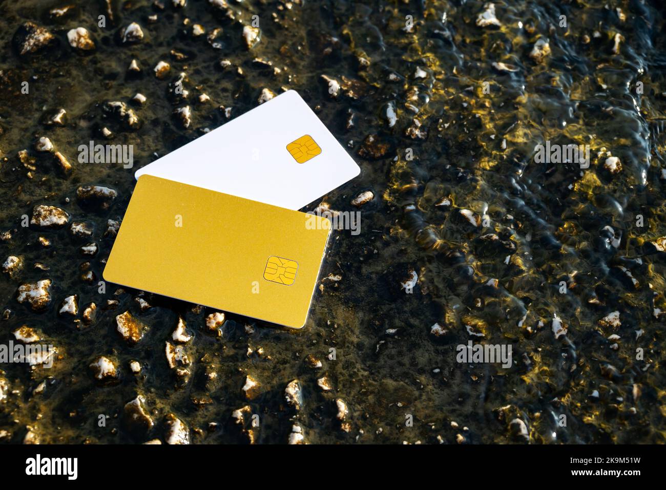 Golden and White Bank Card se trouve sur Stone Pier, recouvert d'eau Moraitika, Corfou, Grèce. Le concept de paiement pour la nature et illimité Banque D'Images