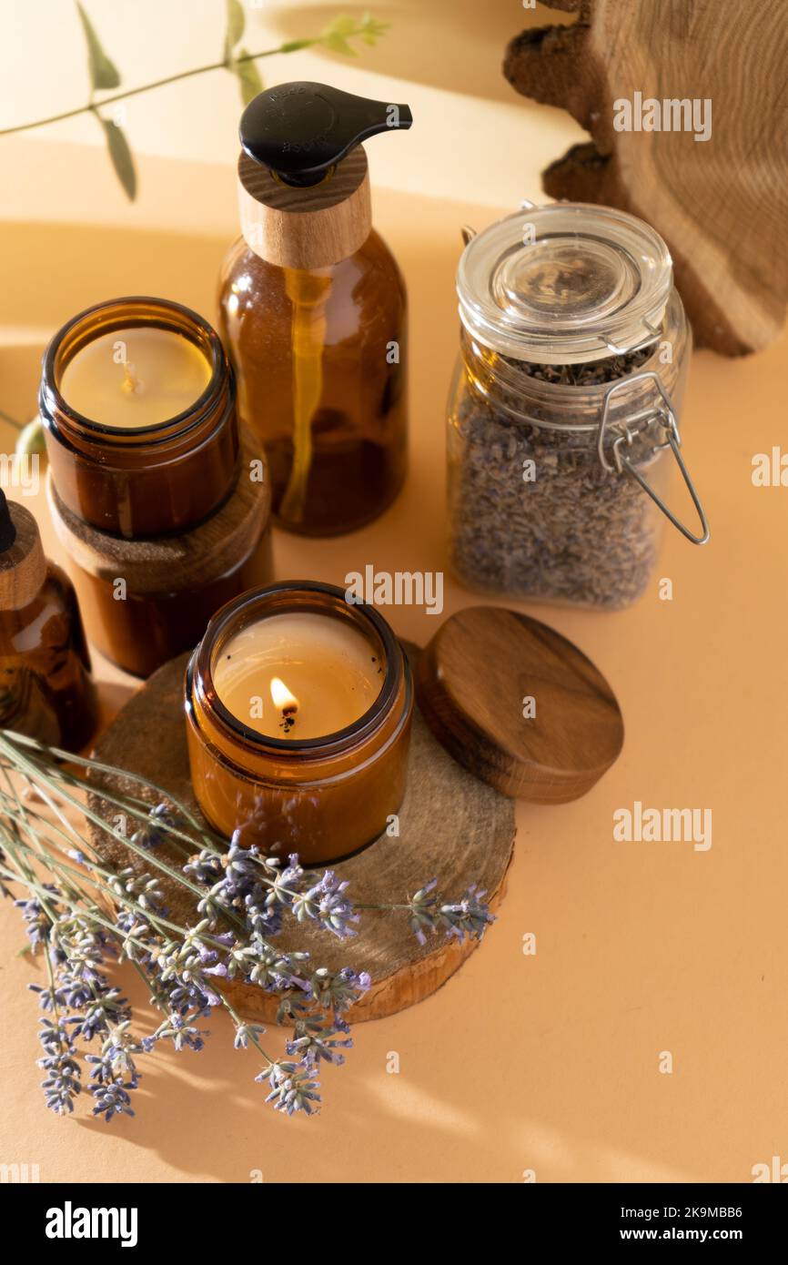 Bougies de soja dans un pot en verre. Aromathérapie. Bougie brûlante et lavande. Couvercle en bois pour bocaux. Arrière-plan beige. Confort et détente. Fait à la main. Décoration d'intérieur. Banque D'Images